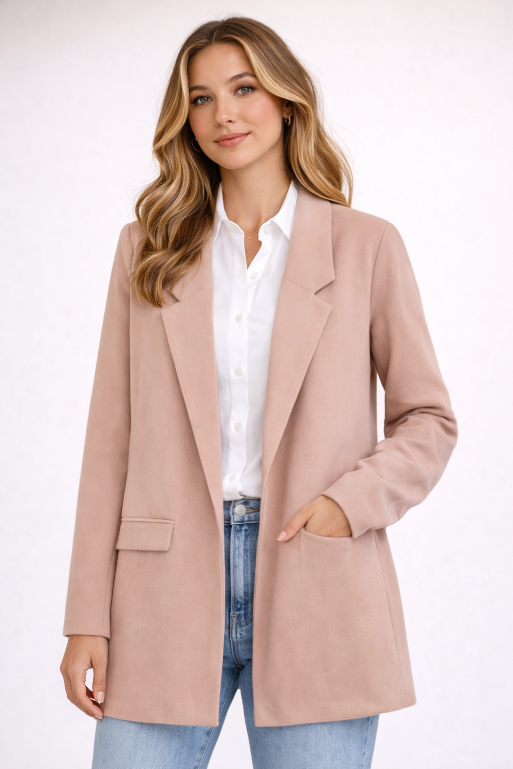 Woman wearing a light pink blazer over a white shirt and blue jeans on a white background