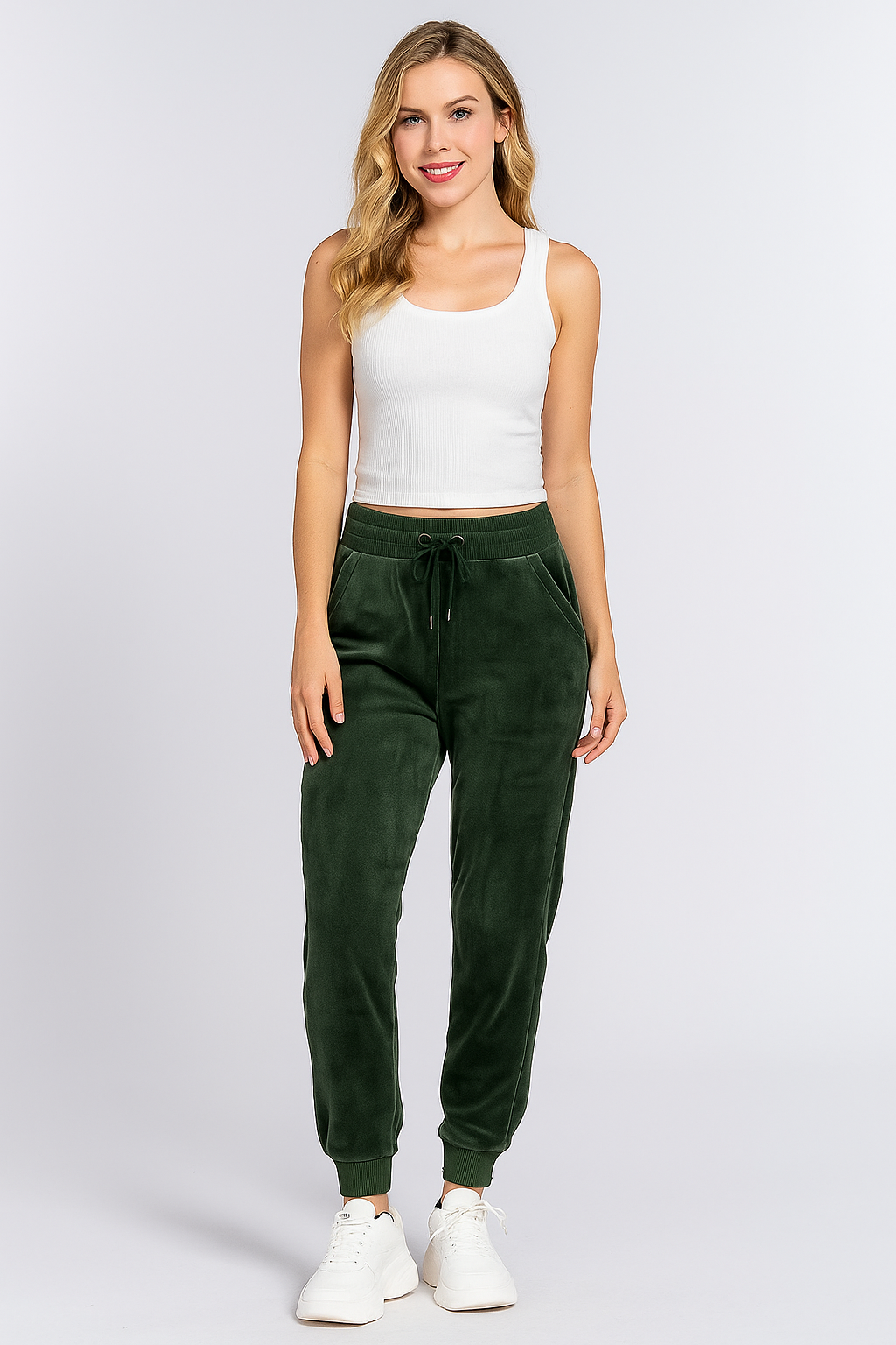 Woman wearing a white tank top and green sweatpants on a white background