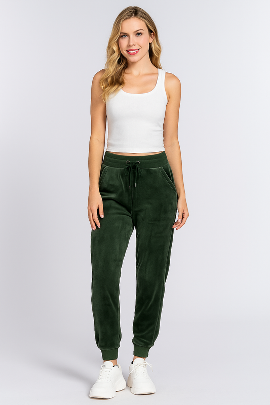 Woman wearing a white tank top and green sweatpants on a white background