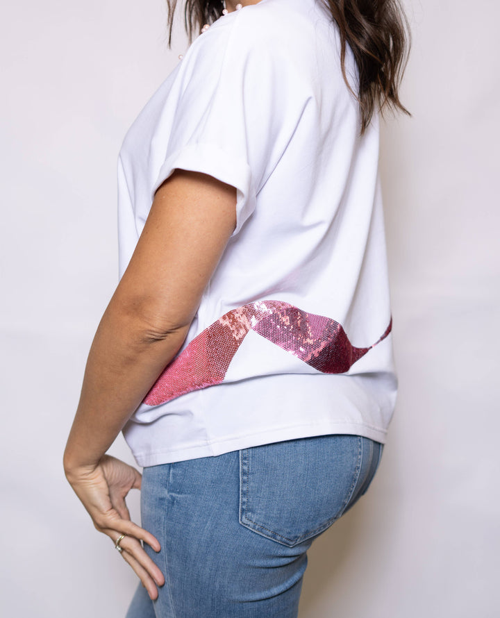 Person wearing a white t-shirt with a red graphic design on a plain background