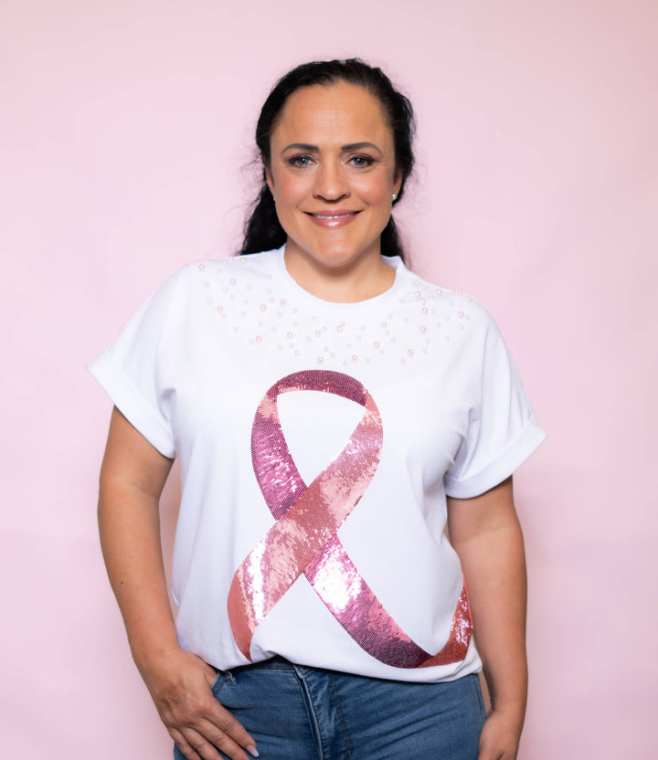 Person wearing a white t-shirt with a pink breast cancer awareness ribbon design on a pink background
