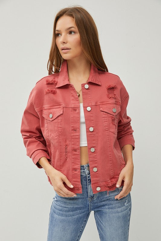 Woman wearing a rust denim jacket and blue jeans on a gray background