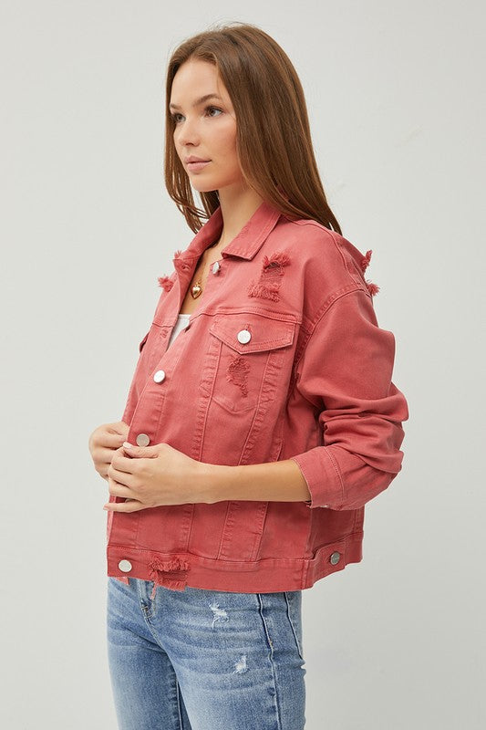 Woman wearing a rust jacket and blue jeans on a light gray background