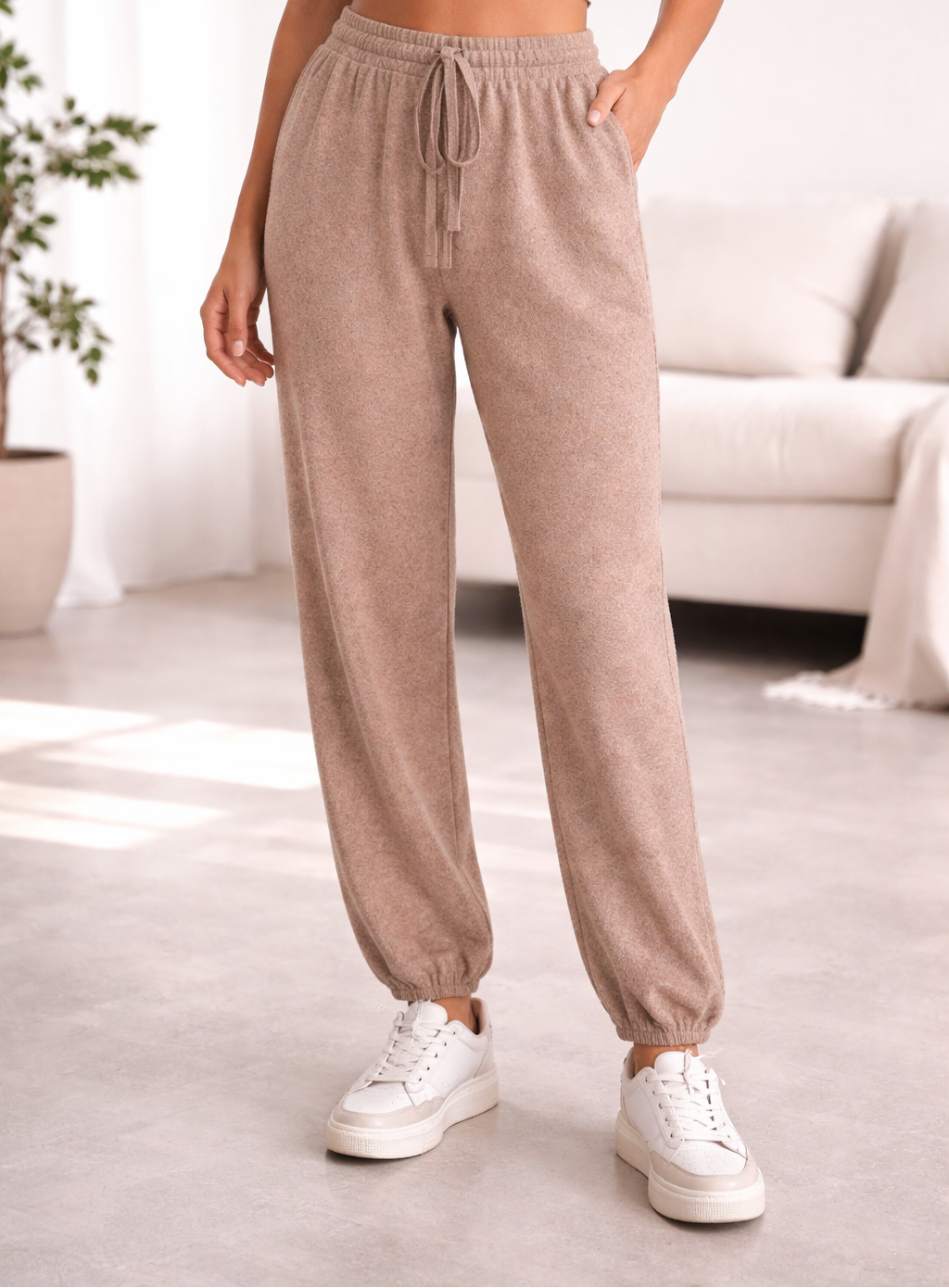 Person wearing beige jogger pants and white sneakers in a living room setting
