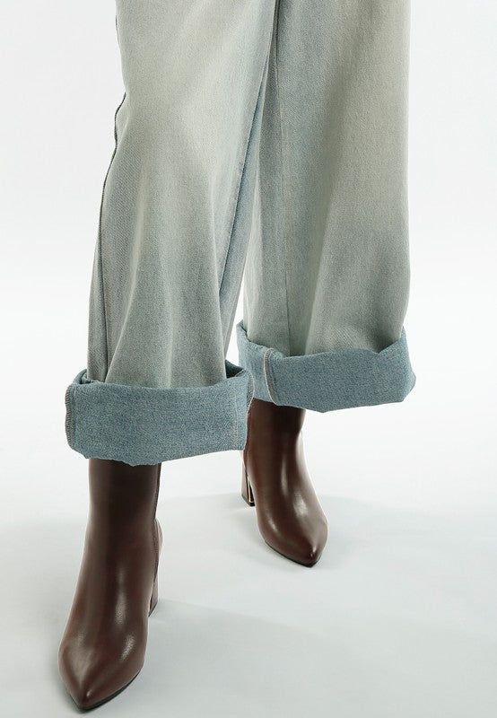 Light gray pants with rolled-up cuffs worn with brown boots on a white background
