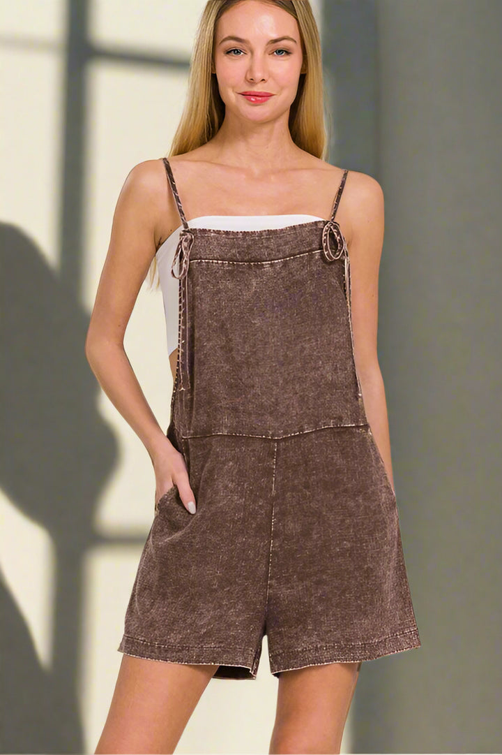 Woman wearing a brown denim overall dress against a neutral background