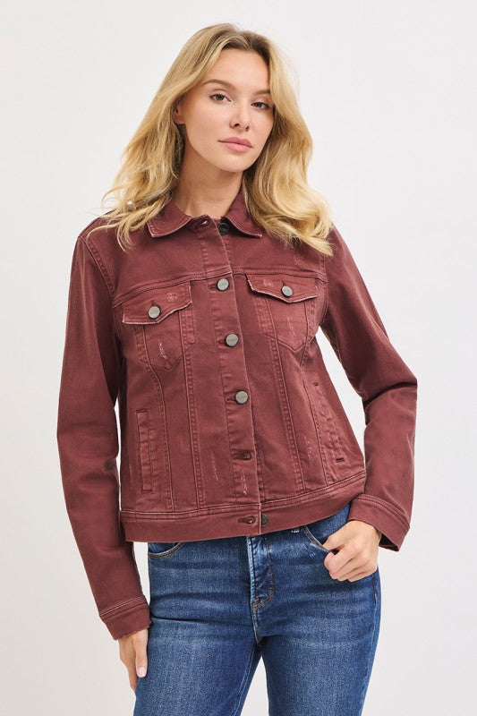 Woman wearing a maroon denim jacket and blue jeans on a white background