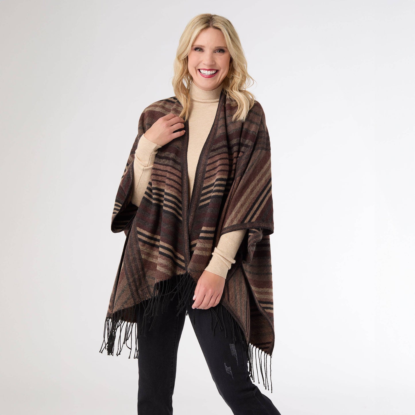 Woman wearing a brown plaid poncho with fringe on a white background