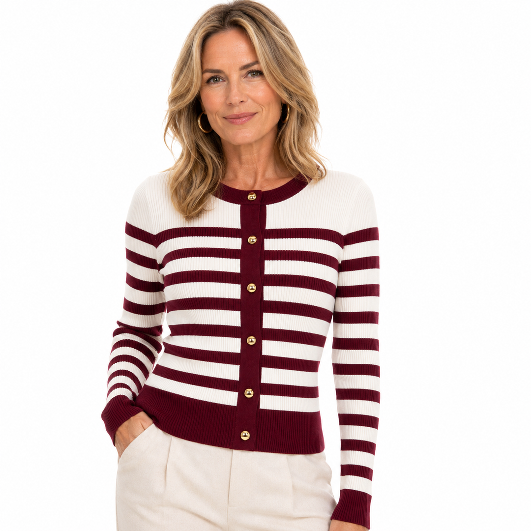 A woman wearing a burgundy and cream striped knit cardigan with gold buttons, paired with cream pants, against a solid white background.