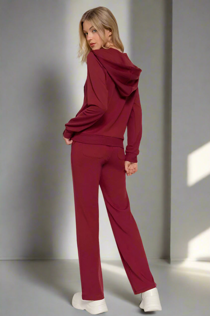 Woman wearing a burgundy tracksuit with a plain background