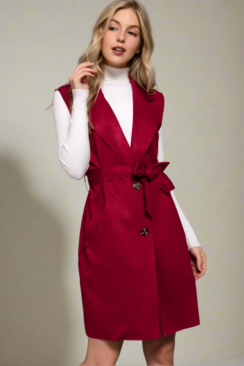 Woman wearing a WINE vest over a white top on a gray background