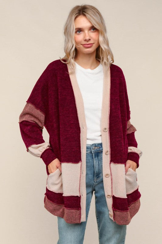 Woman wearing a long, patterned cardigan with a neutral background