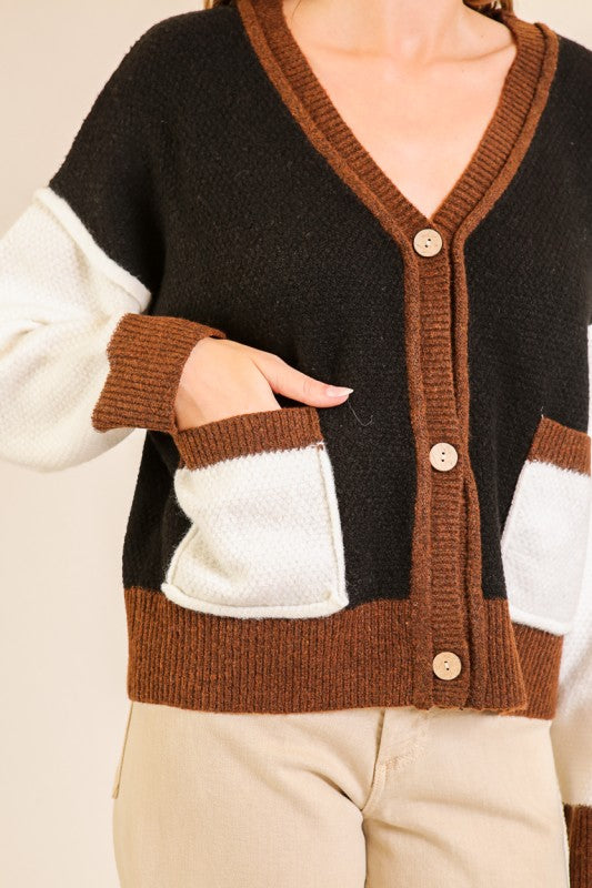Black and brown cardigan with white sleeves worn by a person on a beige background