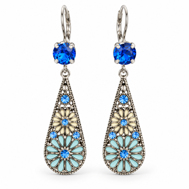 A pair of silver drop earrings with blue gemstones and light blue enamel floral details, shown on a plain white background.