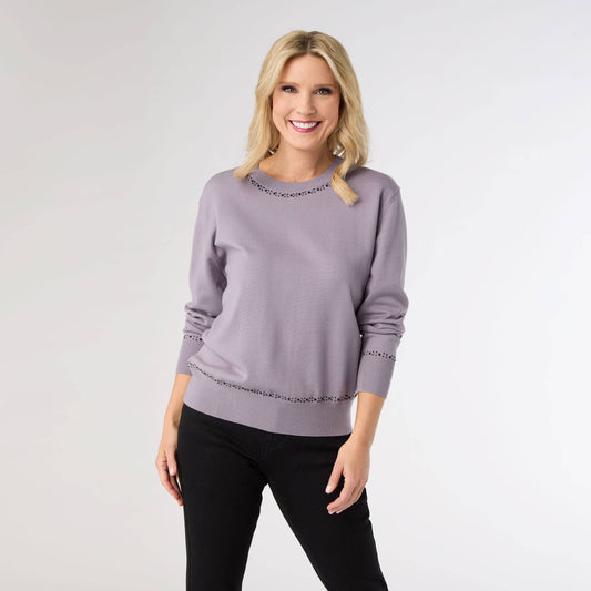 Woman wearing a light purple sweater with jeweled details on a white background