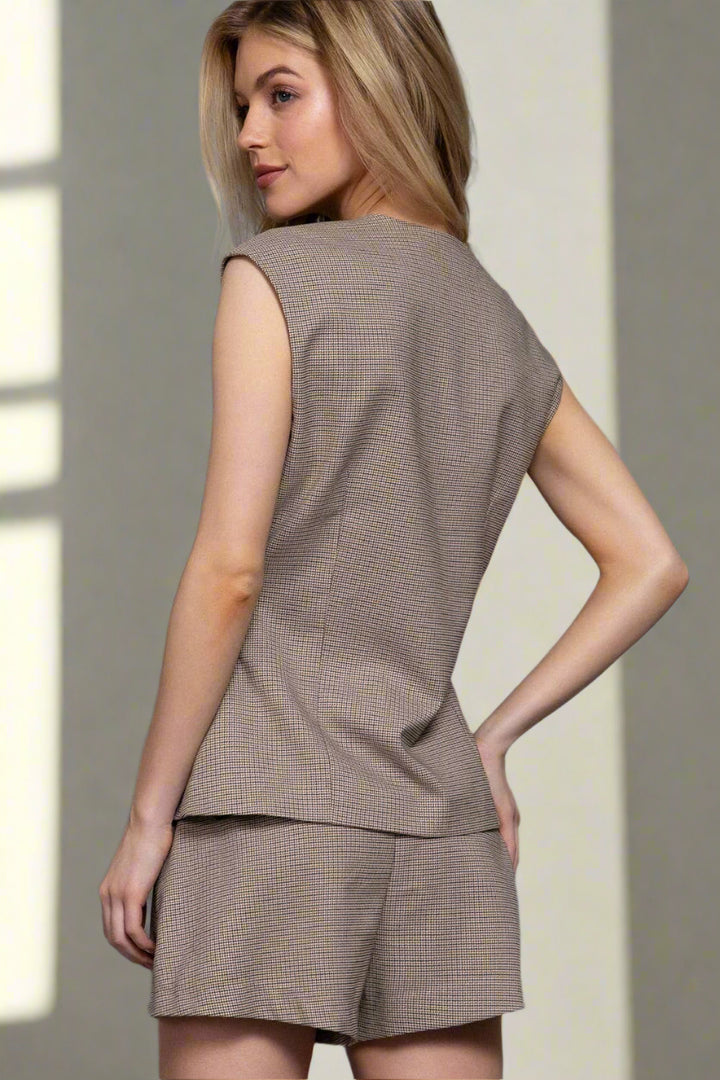 Woman wearing a brown sleeveless top and shorts set against a gray background