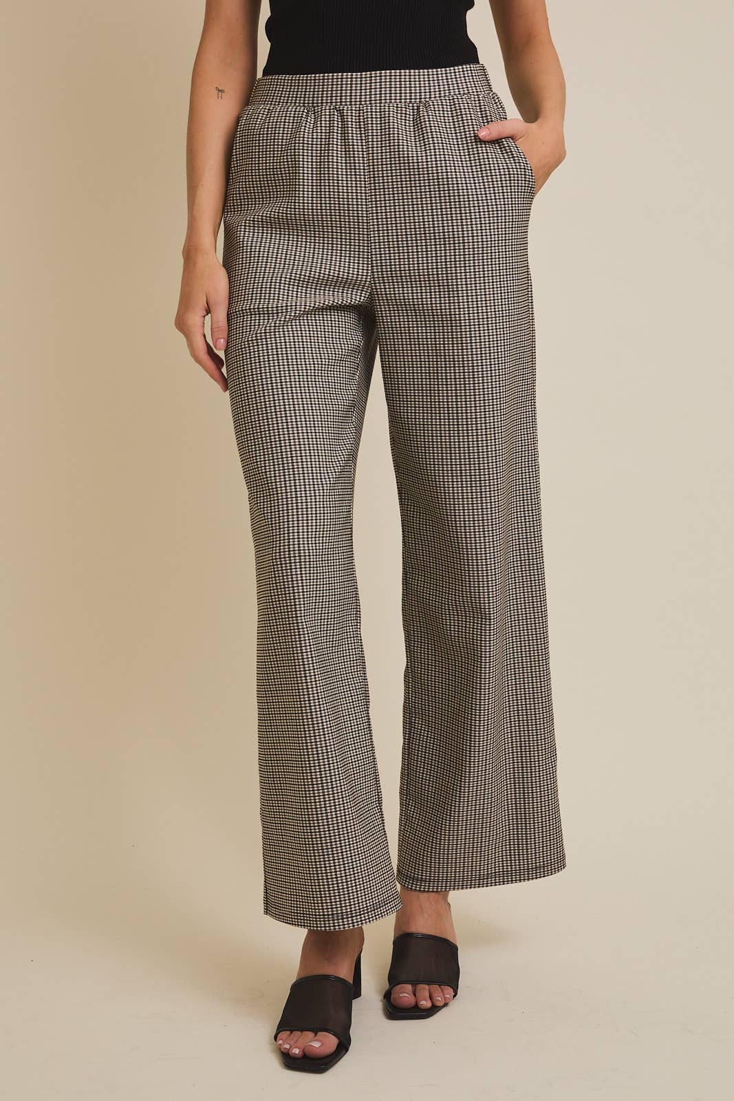 Person wearing checkered pants on a beige background