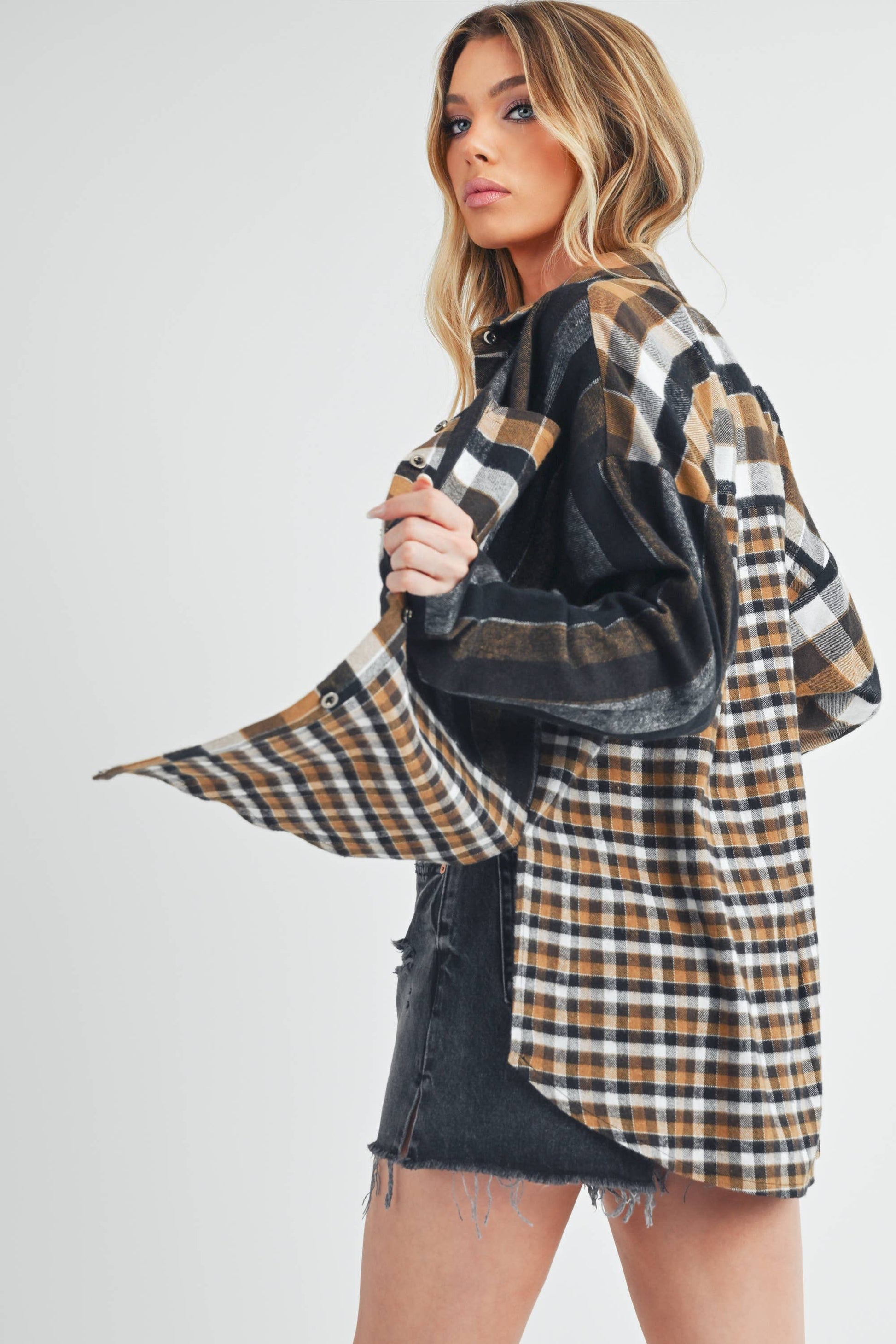 Woman wearing a plaid shirt over a black top with a white background