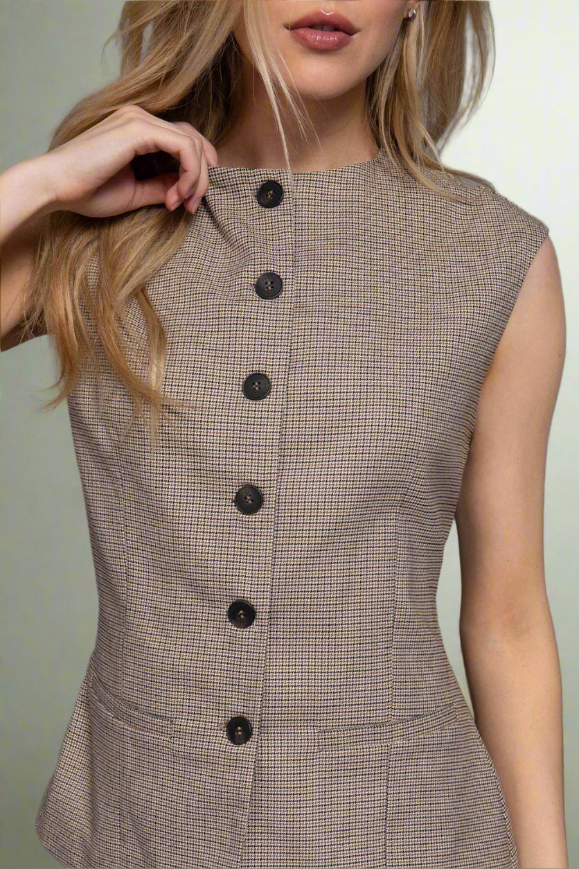 Woman wearing a brown checkered dress with black buttons on a gray background