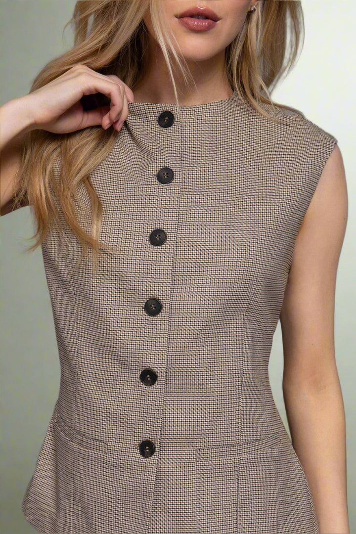 Woman wearing a brown checkered dress with black buttons on a gray background