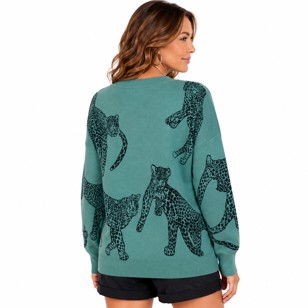 A woman shown from the back wearing a teal crewneck sweatshirt with a black leopard print pattern, paired with black shorts, against a plain white background.