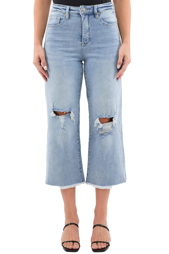 Light blue jeans with distressed knees worn by a model on a white background.