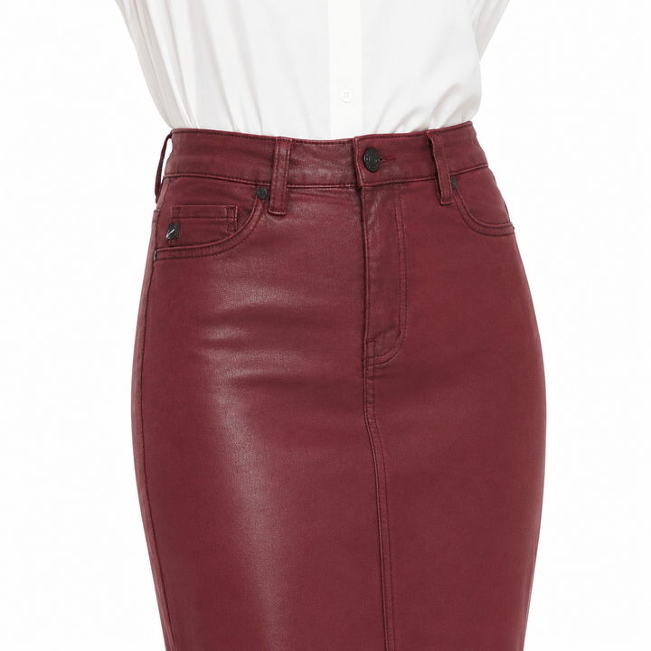 A close-up of a high-waisted burgundy faux-leather skirt with a button closure and belt loops, styled with a white top against a plain white background.