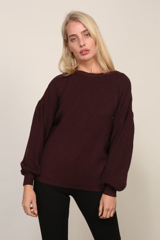 Woman wearing a burgundy sweater against a plain background