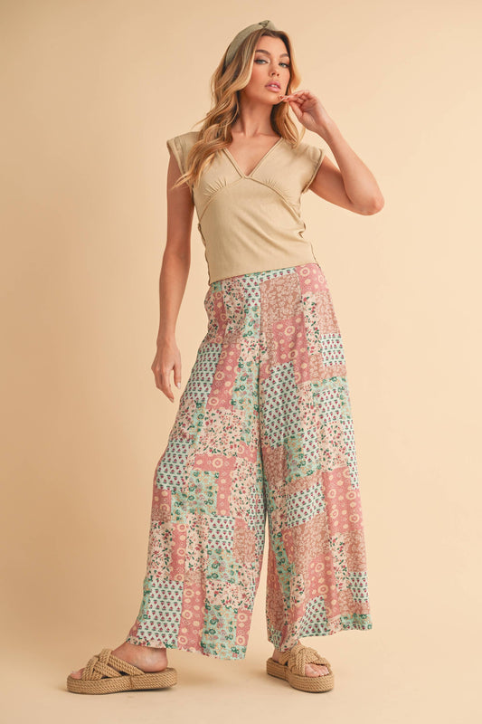 Woman wearing a beige top and patterned pants on a beige background
