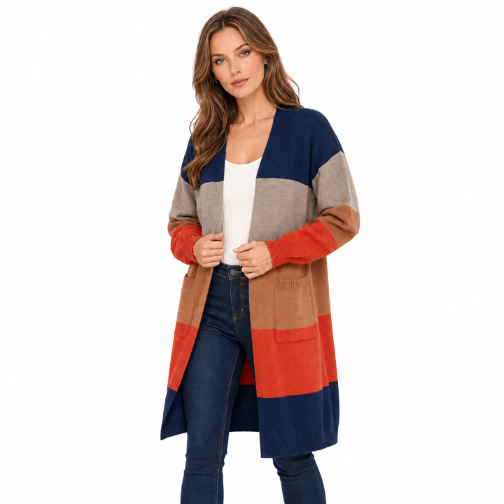 A woman modeling a long color-block knit cardigan with navy, taupe, beige, brown, and rust-orange panels, worn over a white top and dark blue jeans against a plain white background.