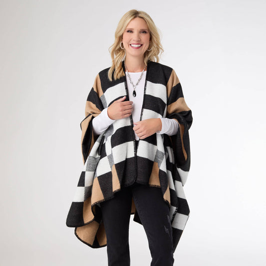 Woman wearing a black, white, and beige striped poncho on a white background