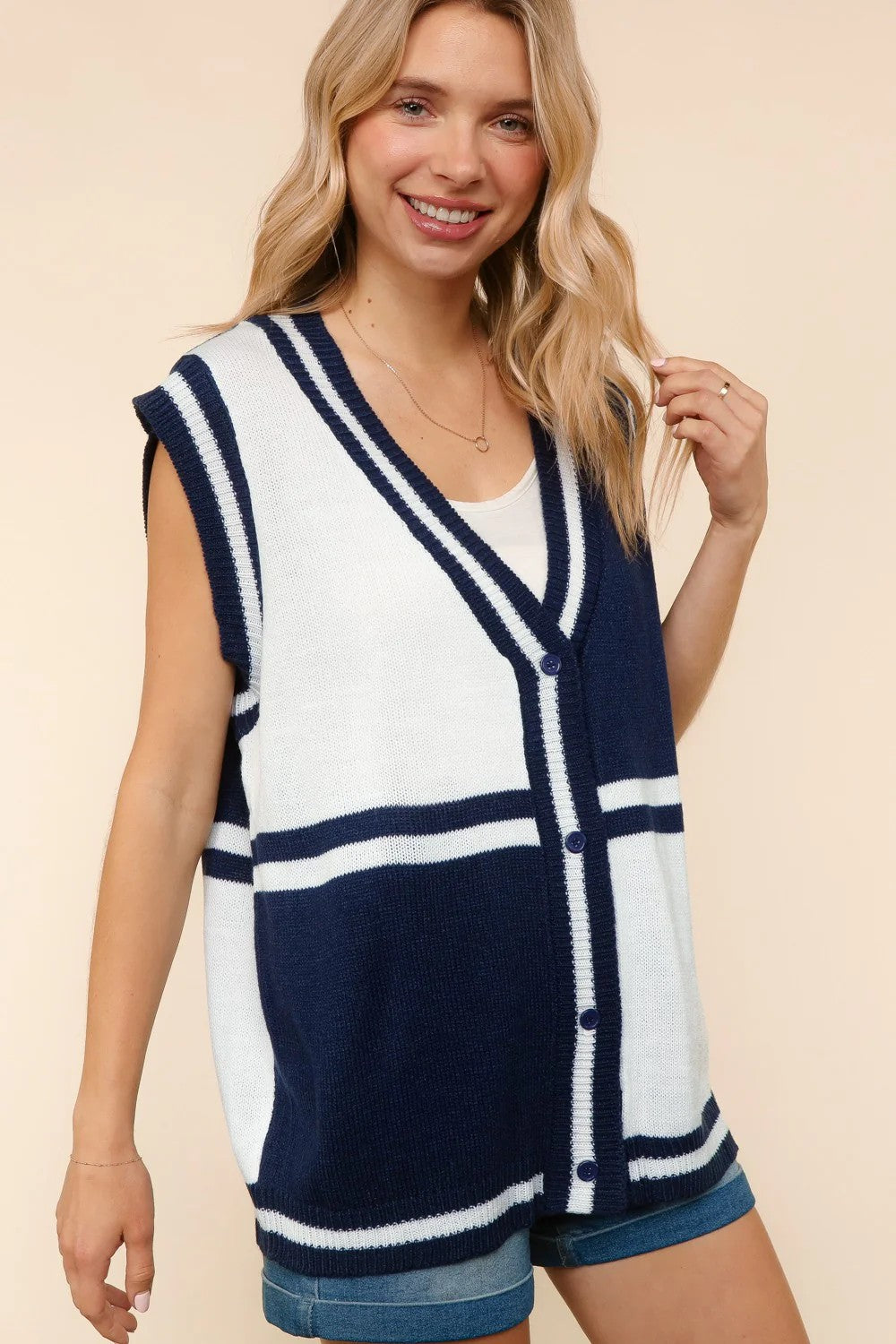 Woman wearing a navy and white striped sleeveless cardigan on a beige background