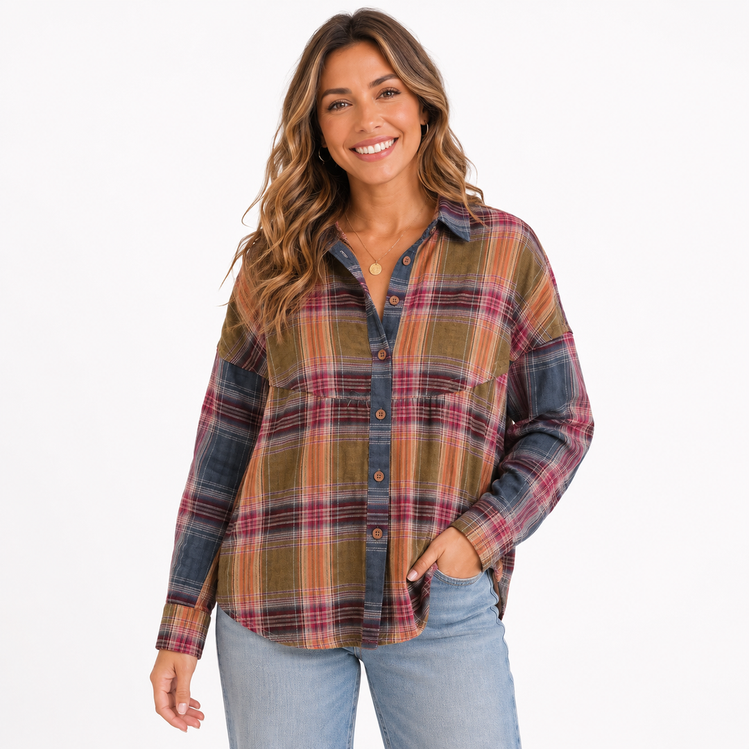 A woman modeling a long-sleeve plaid button-up shirt with a muted green, red, and blue pattern, paired with light blue jeans, against a plain white background.