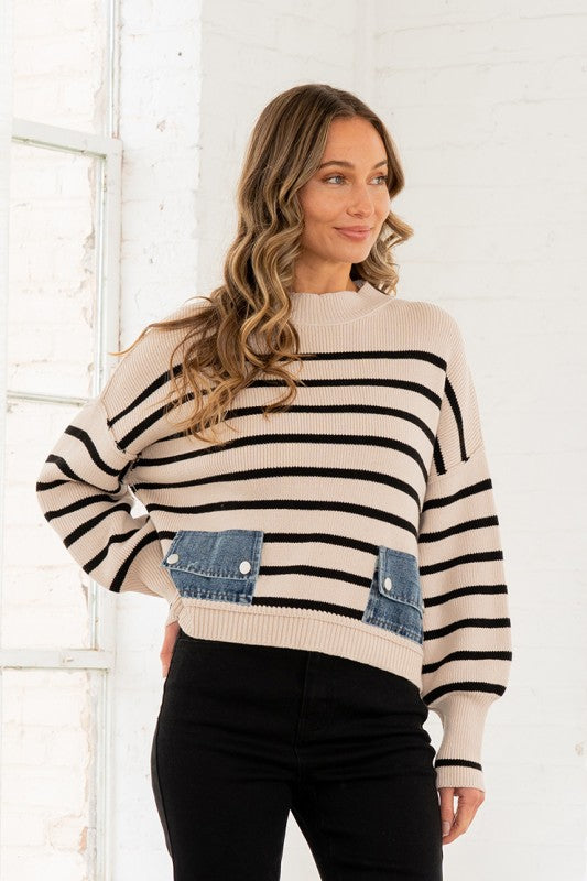 Woman wearing a striped sweater with denim pocket against a white wall