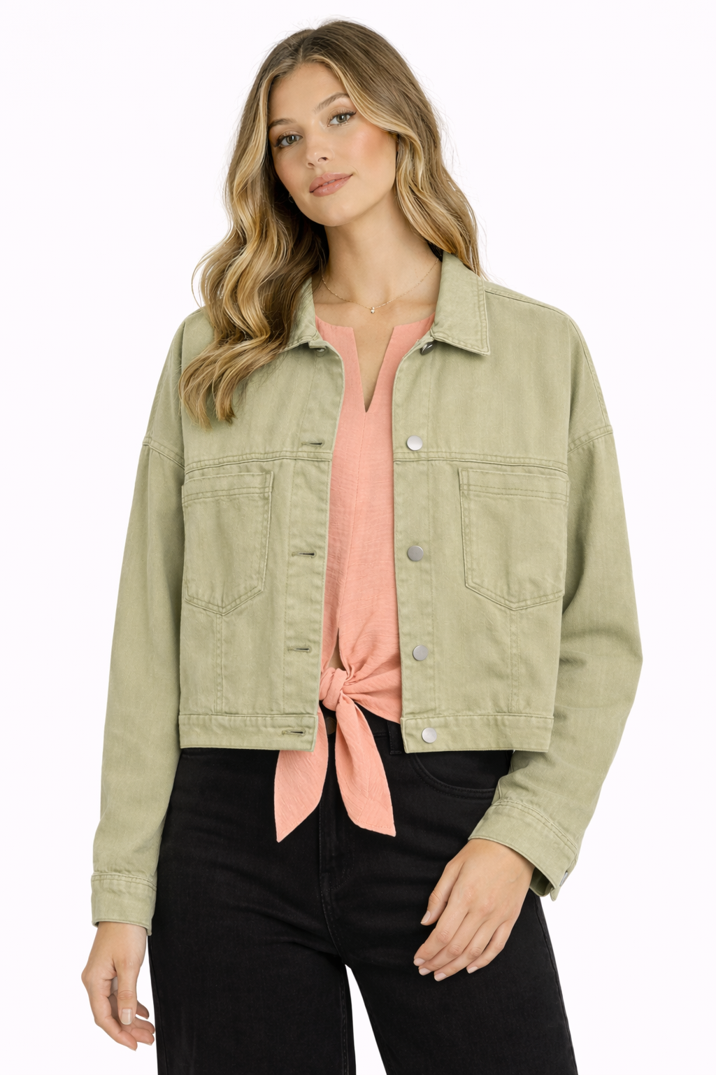 Woman wearing a light green jacket over a pink top with black pants on a white background
