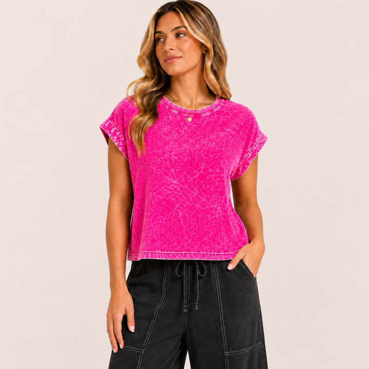 Woman wearing a bright pink t-shirt and black pants on a light beige background