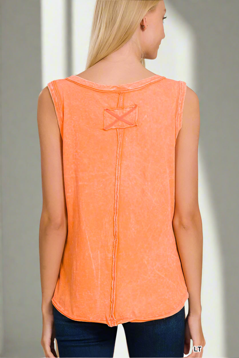 Woman wearing an orange sleeveless top with a decorative back detail on a plain background