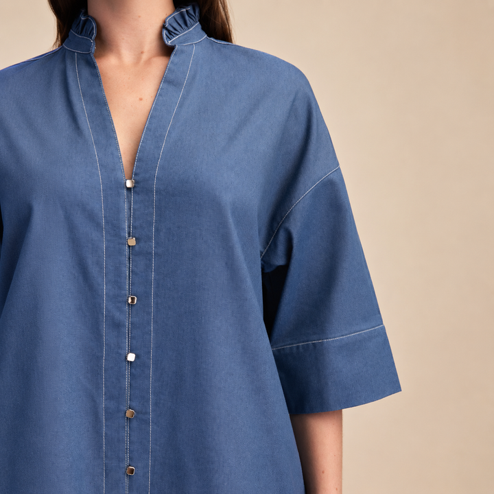 Blue denim shirt worn by a person on a beige background