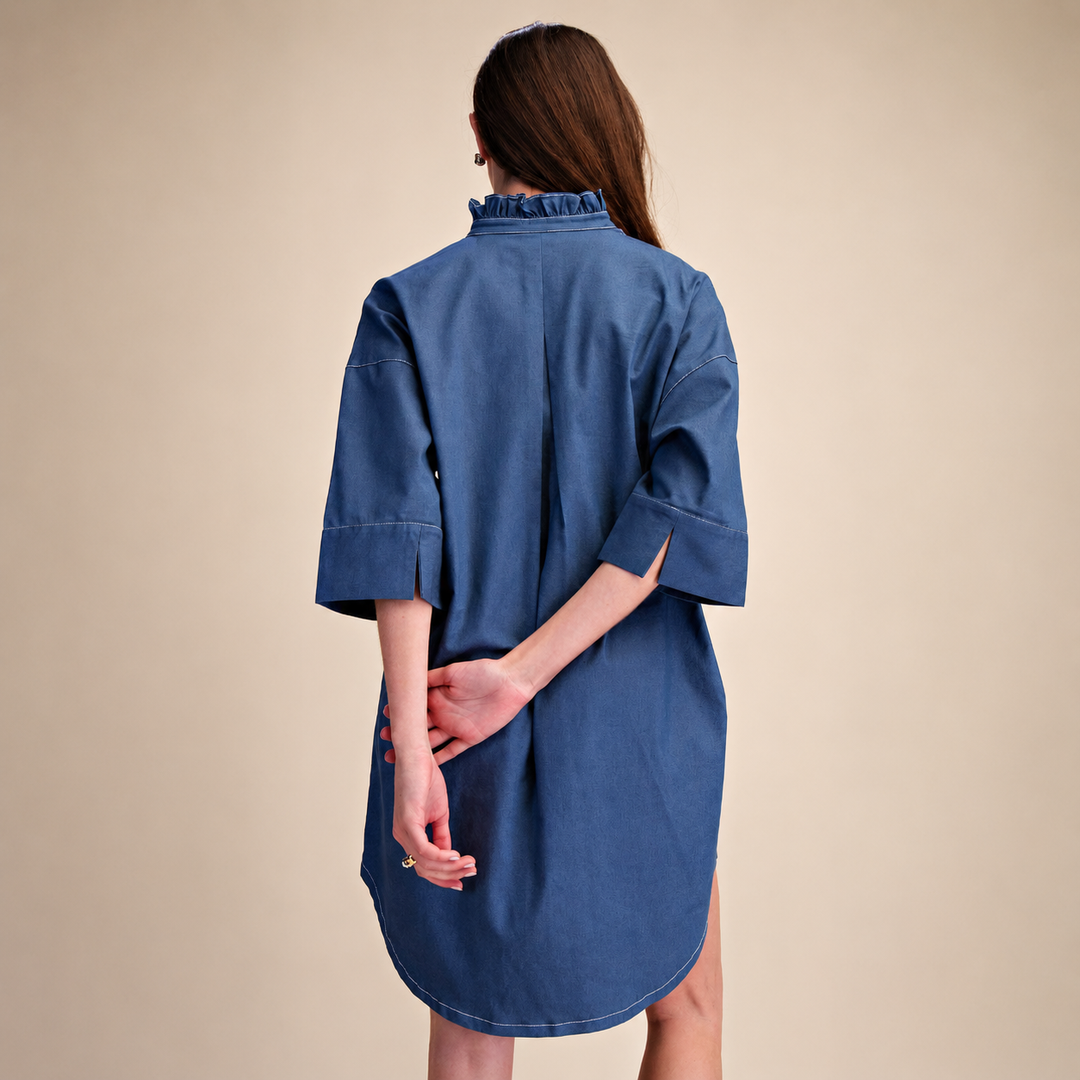 Woman wearing a blue denim dress against a beige background