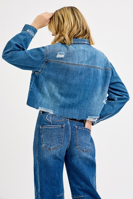 Person wearing a blue denim jacket and jeans on a white background