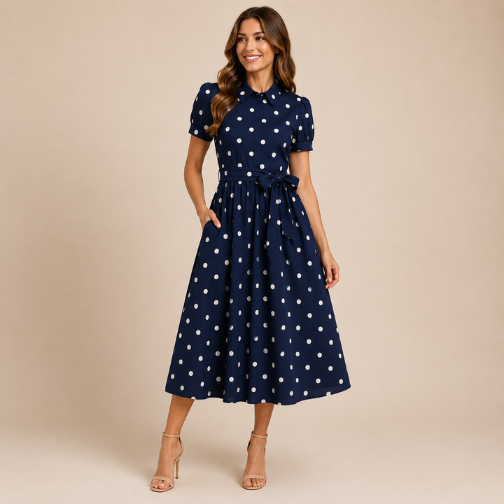Woman wearing a navy blue dress with white polka dots on a beige background
