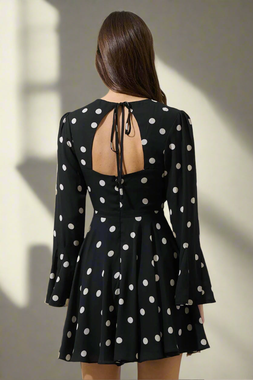 Black polka dot dress with long sleeves and open back on a gray background
