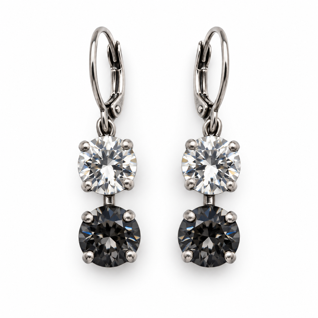 A pair of leverback drop earrings featuring a clear round gemstone and a dark gray round gemstone in silver-toned prong settings, shown against a plain white background.