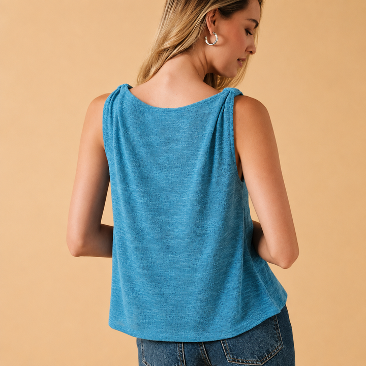Woman wearing a blue sleeveless top against a beige background