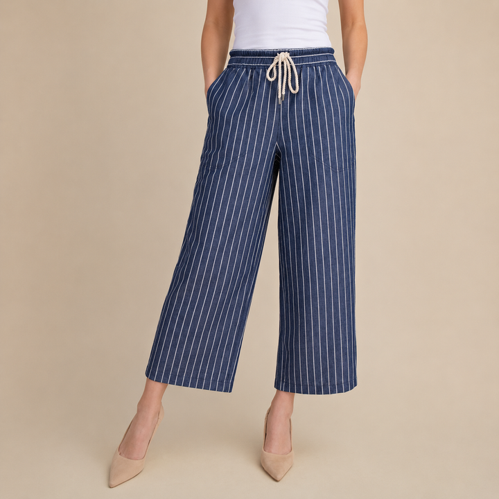 Navy pinstripe pants with a white top on a beige background