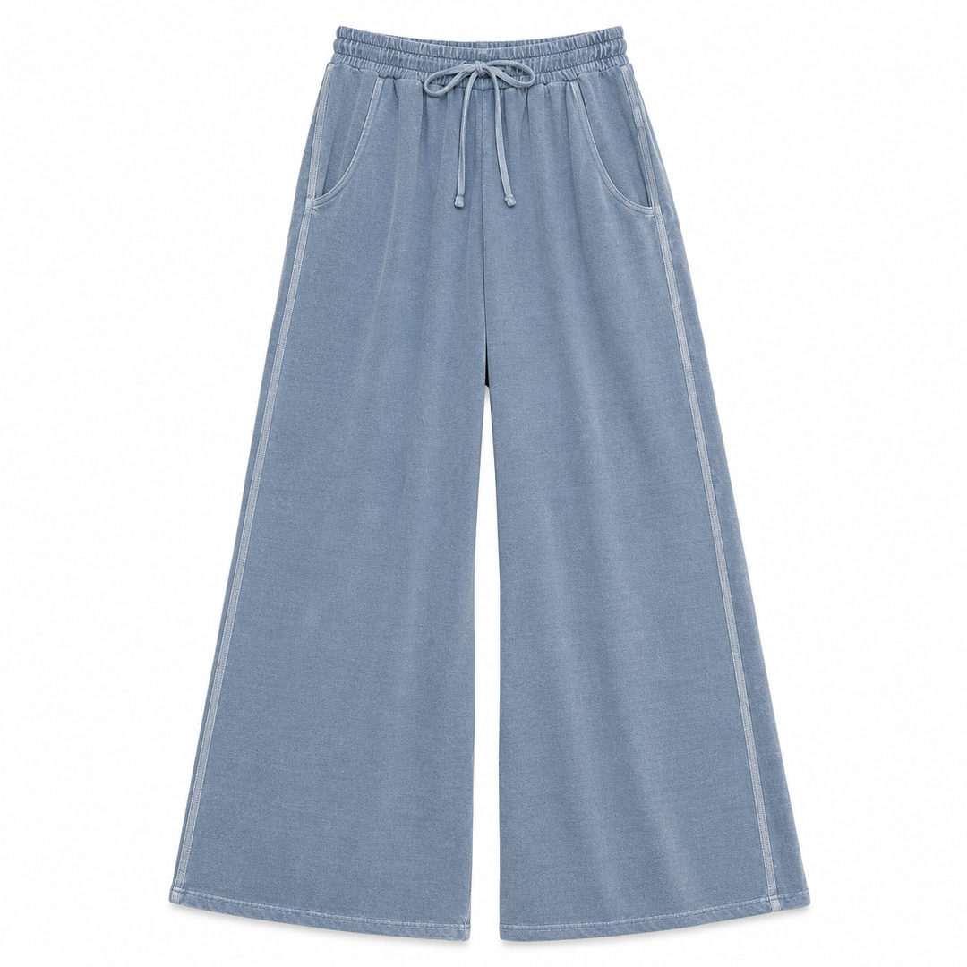 Light blue wide-leg lounge pants with an elastic drawstring waist, side pockets, and white piping details along the outer seams, shown against a plain white background.