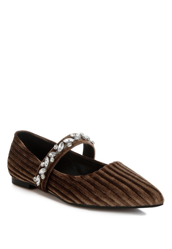 Brown velvet flat shoe with a decorative strap on a white background