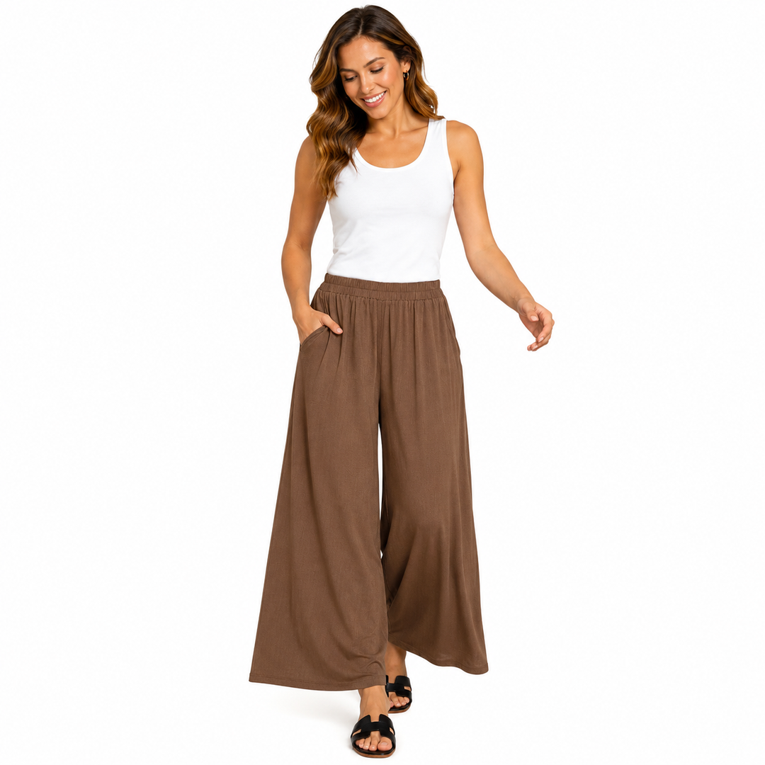 Woman wearing a white tank top and brown wide-leg pants on a white background