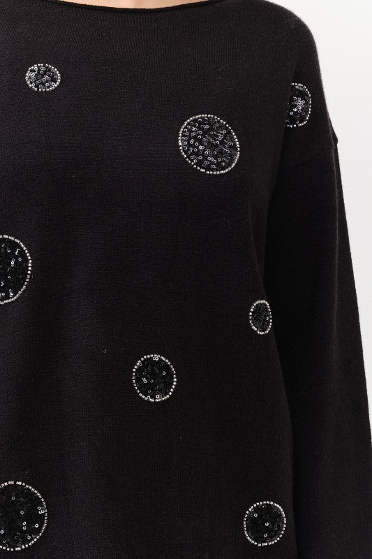 Black sweater with circular patterns on a plain background
