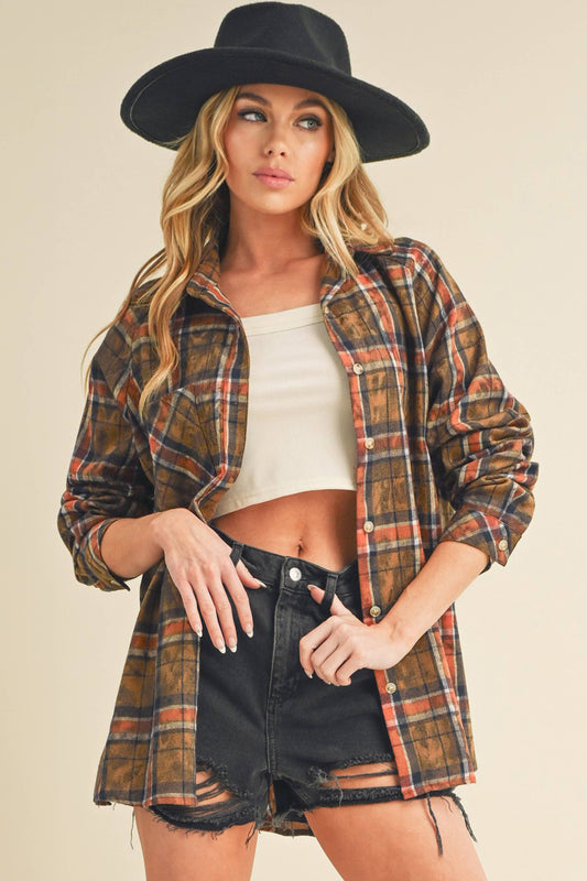 Woman wearing a plaid shirt, white top, and black shorts with a black hat on a beige background